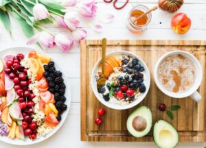 A breakfast bowl with oats, berries, walnuts, and a glass of water on a sunlit kitchen table.